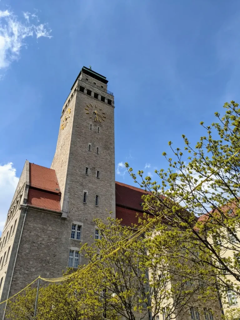 Turm des Rathauses Neukölln hinter frischem Laub