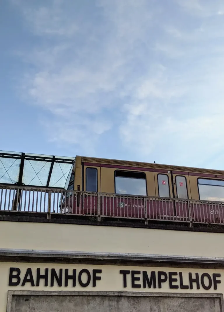 Bahnbrücke am Tempelhofer Damm mit dem Schriftzug Bahnhof Tempelhof, darüber eine S-Bahn