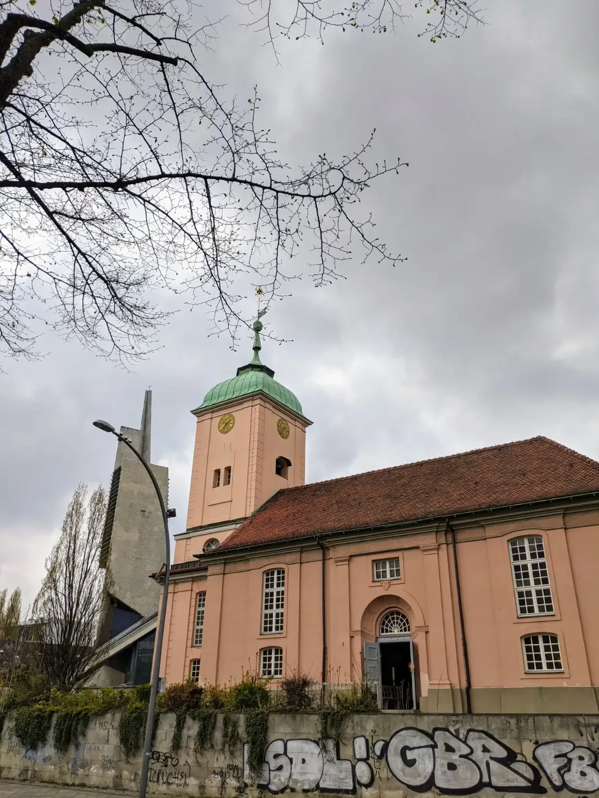 Rosa verputzte Dorfkirche Schöneberg mit grünem Turmhelm an der Hauptstraße