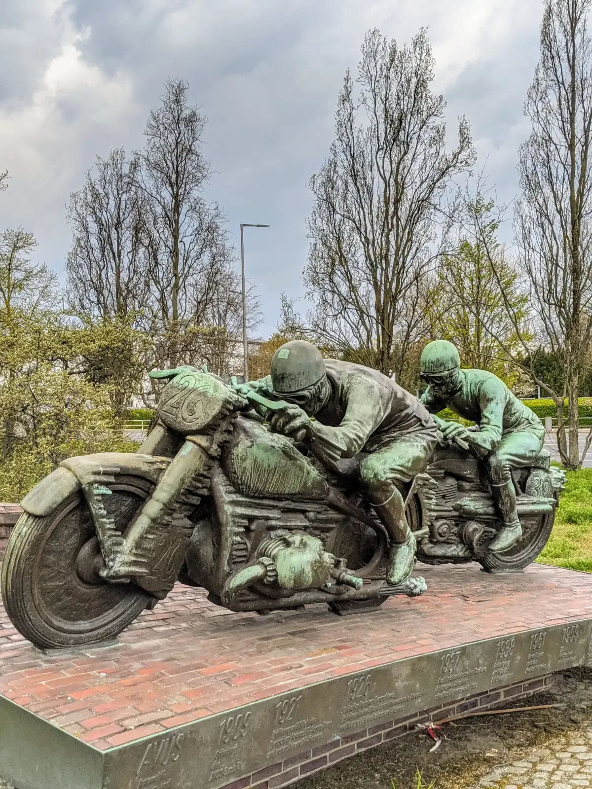 Bronzeskulptur zweier Motorradrennfahrer auf rotem Klinkersockel an der AVUS-Einfahrt