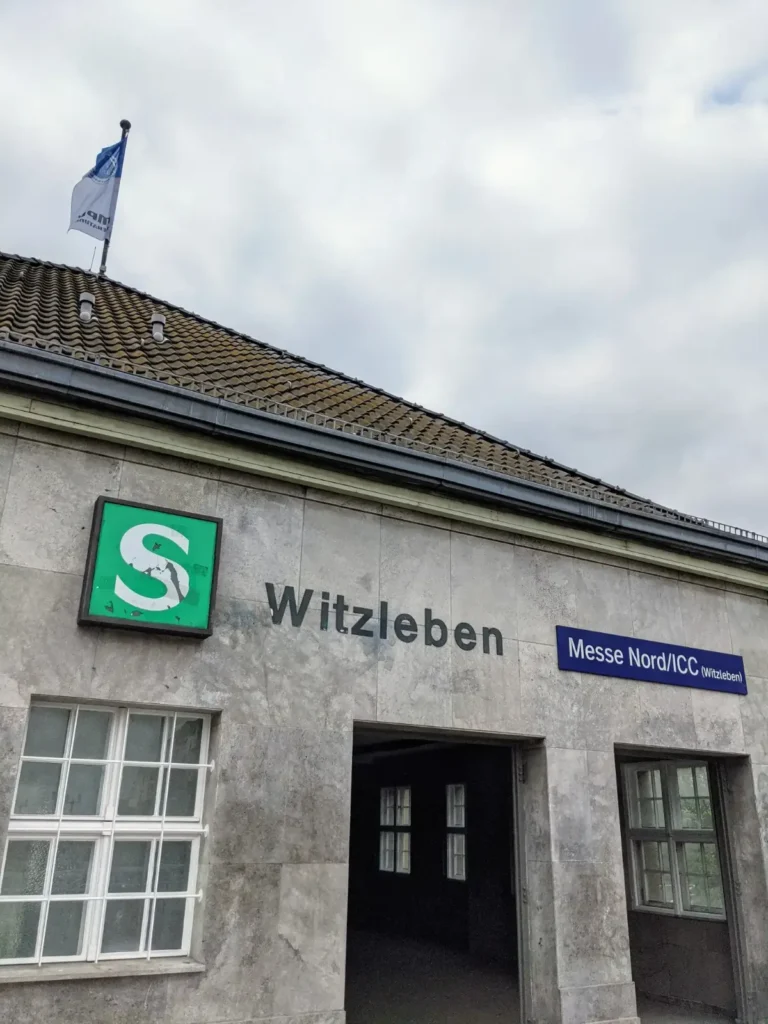 Empfangsgebäude des Bahnhofs Messe Nord in Berlin mit altem Schriftzug Witzleben und blauem Stationsschild