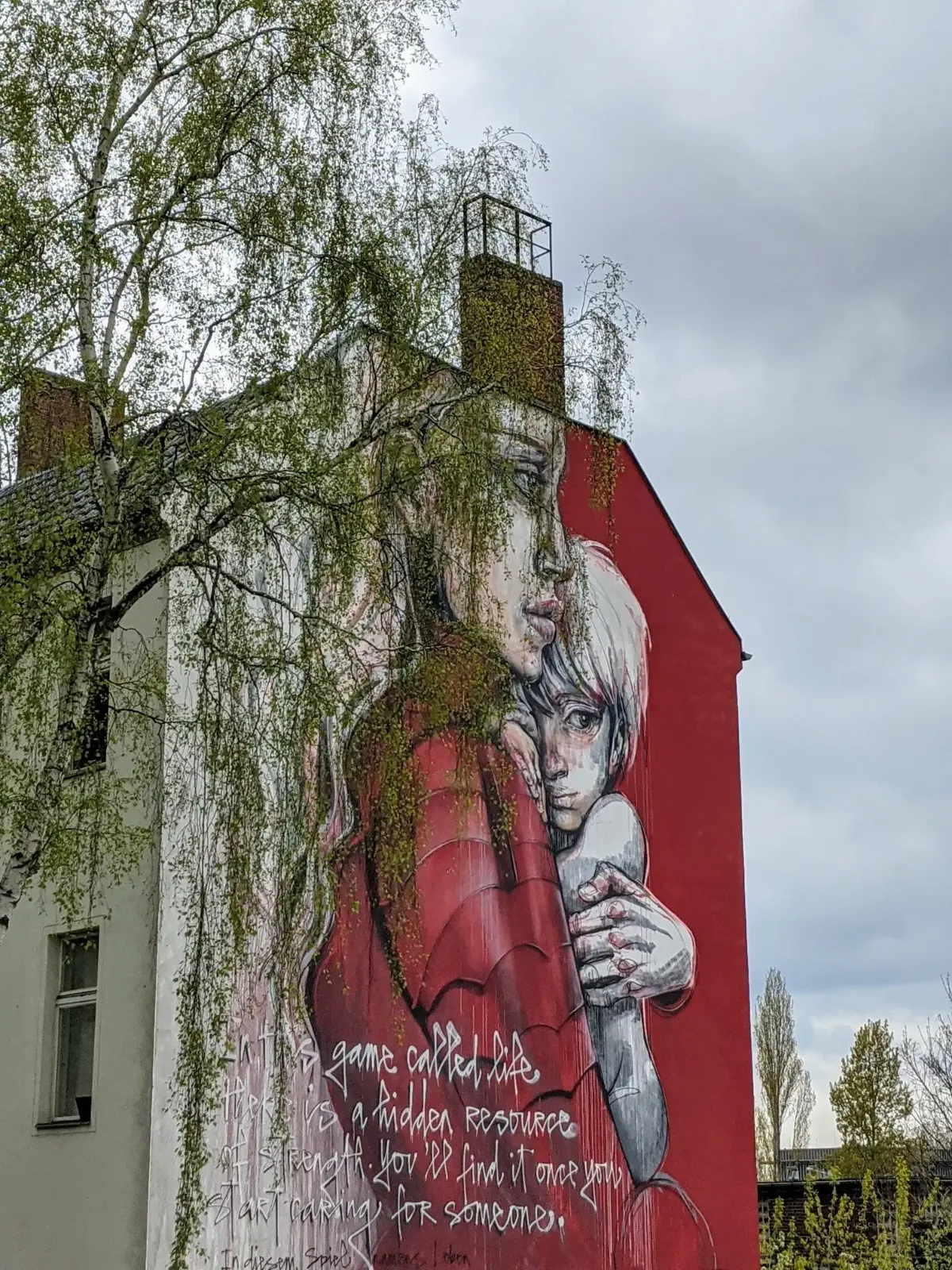 Wandbild This game called life von Herakut an einer roten Brandwand in der Sickingenstraße in Berlin-Moabit: Frau im roten Gewand umarmt ein blondes Kind