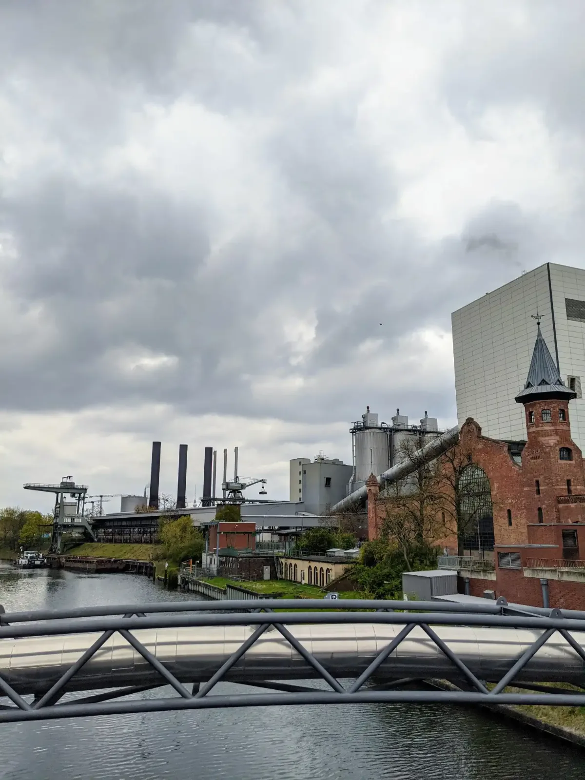 Berlin-Spandauer Schifffahrtskanal mit Fußgängerbrücke, Backsteinbau mit Türmchen, Schornsteinen und Kränen