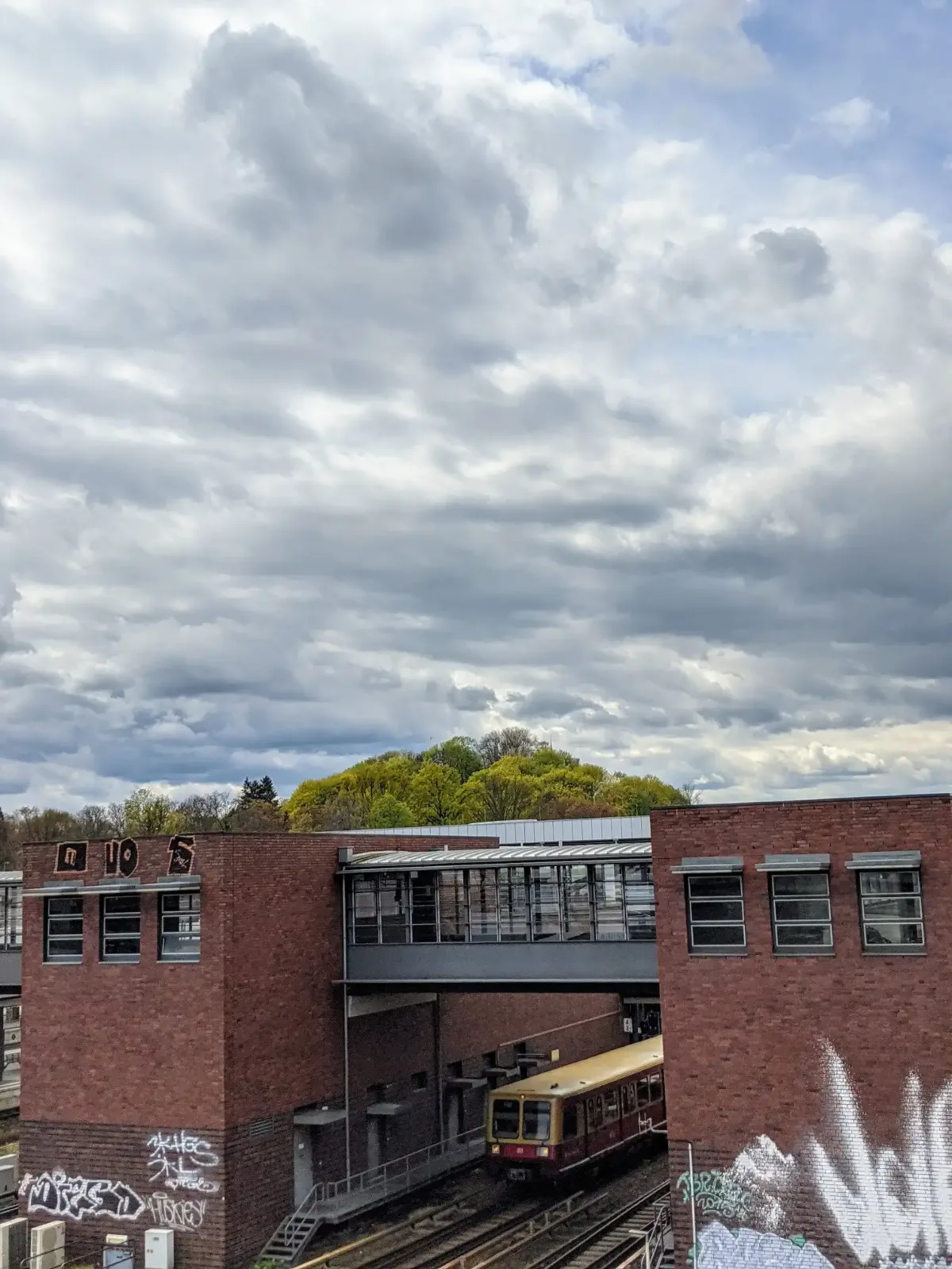 Rote Backsteinbauten mit verglastem Übergang und S-Bahn am Bahnhof Gesundbrunnen