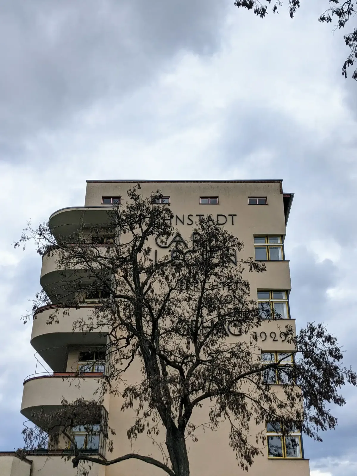 Kopfbau der Wohnstadt Carl Legien mit runden Balkonen und Schriftzug an der Erich-Weinert-Straße