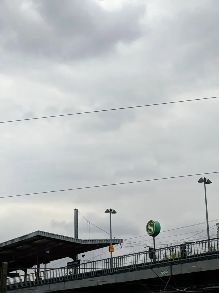 Bahnsteig des S-Bahnhofs Greifswalder Straße von der Straße aus mit Geländer, Laternen und S-Zeichen