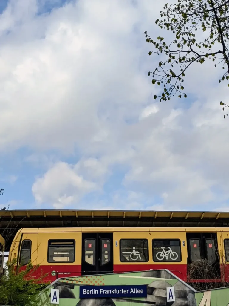 Gelb-rote S-Bahn am Bahnhof Frankfurter Allee mit Bahnhofsschild