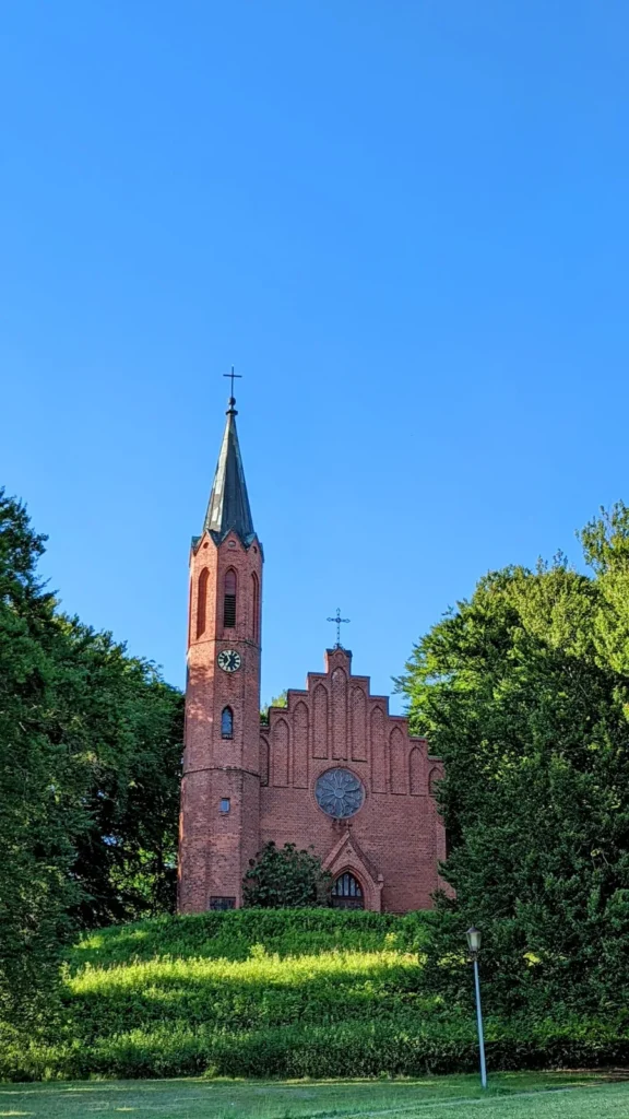 Neugotische Backsteinkirche St. Johannis in Sassnitz hinter Bäumen