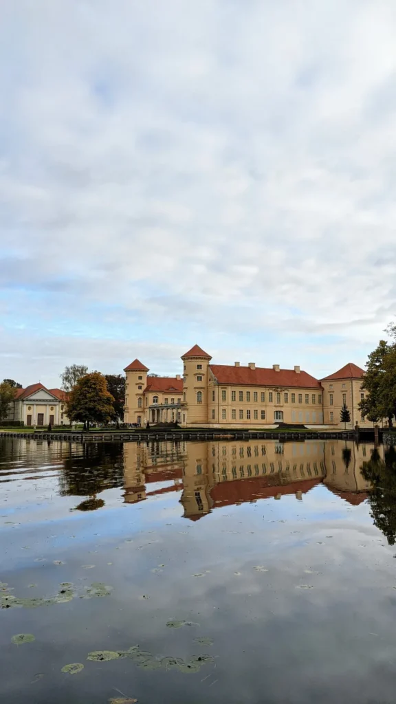 Schloss Rheinsberg mit Spiegelung im Wasser, im Vordergrund Seerosenblätter