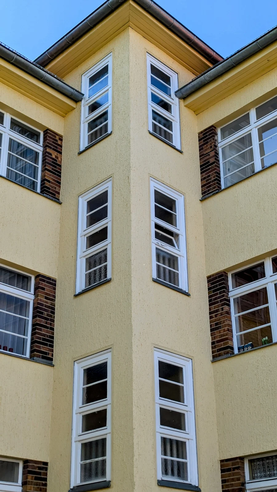 Gelb verputztes Wohnhaus mit vorspringendem Treppenhaus und weißen Sprossenfenstern in Schmargendorf