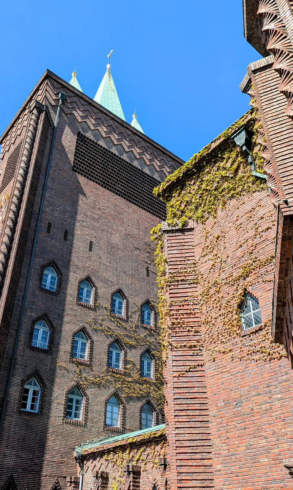 Backsteinturm der Kreuzkirche mit Zickzackfriesen und grünen Kupferspitzen am Hohenzollerndamm