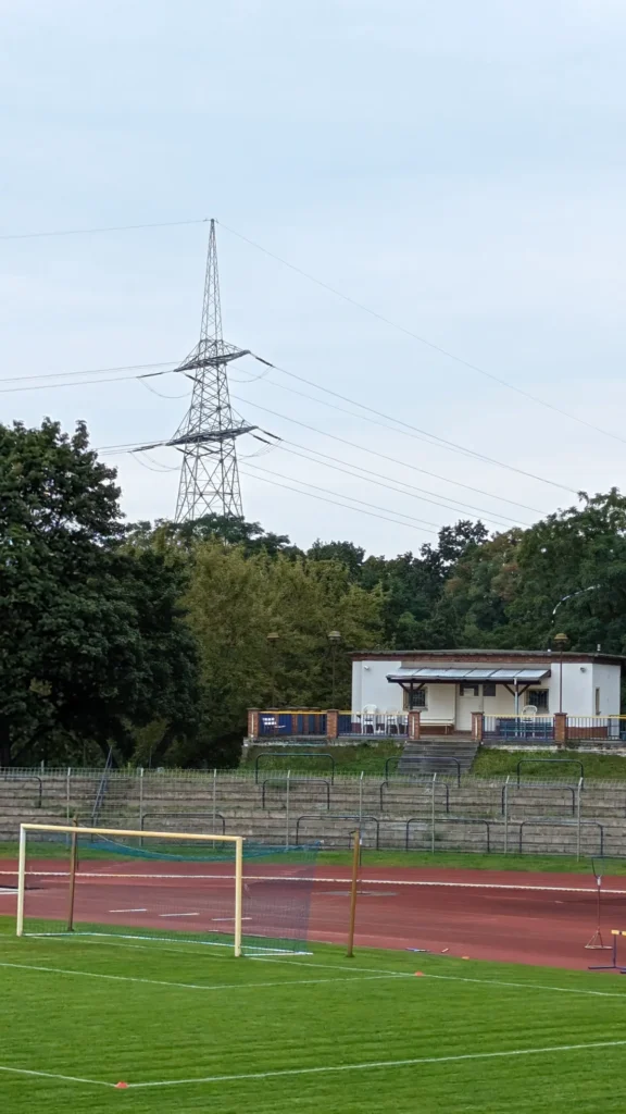 Blick über Rasen und rote Laufbahn im Stadion am Quenz auf die Gegenseite, dahinter ein Strommast