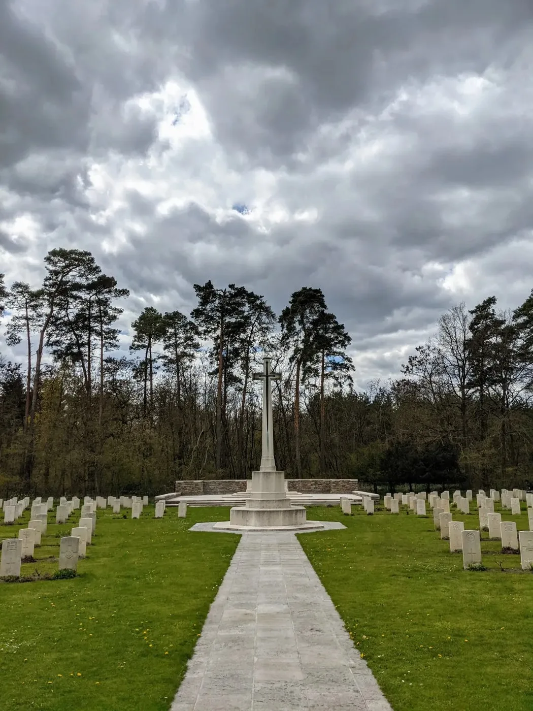 Gräberfeld mit gleichen Grabsteinen, ein Plattenweg führt zu einem Kreuz