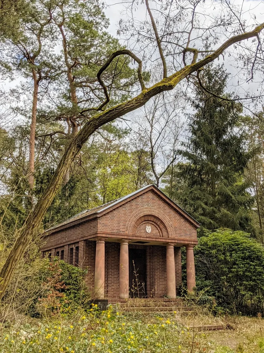 Backsteinmausoleum mit Säulenvorbau zwischen Kiefern
