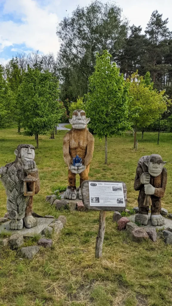 Gruppe geschnitzter Holzfiguren mit Infotafel auf einer Wiese