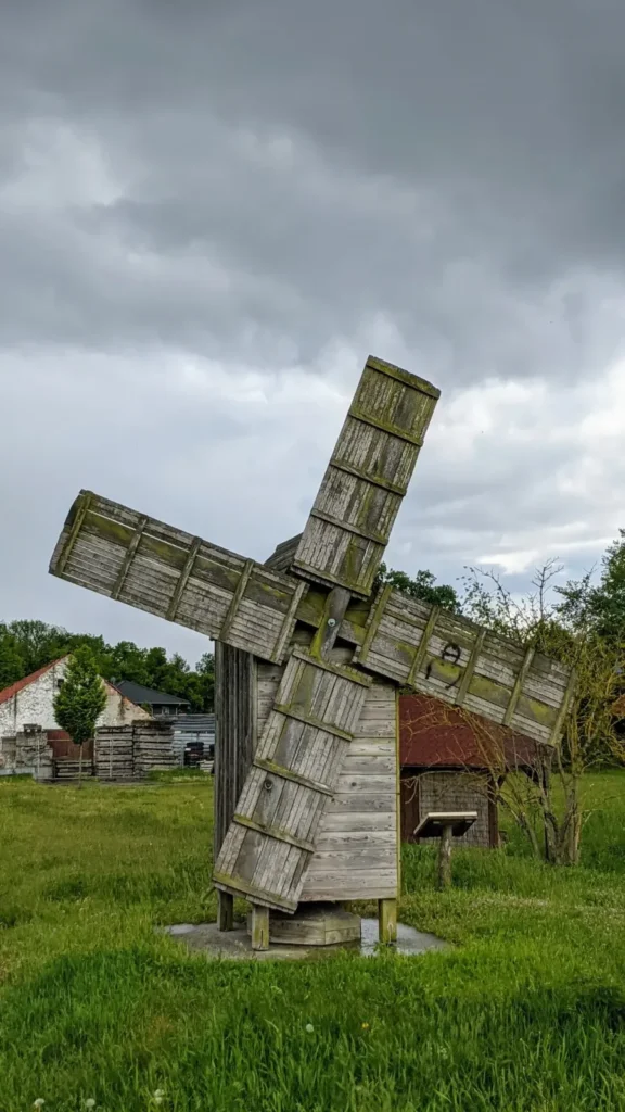 Holzwindmühle, im Hintergrund ein Bauernhaus
