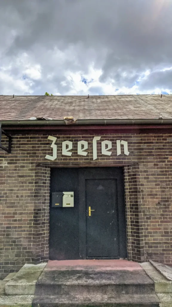 Backsteingebäude mit Schriftzug „Zeesen“ in Frakturschrift und dunkler Doppeltür