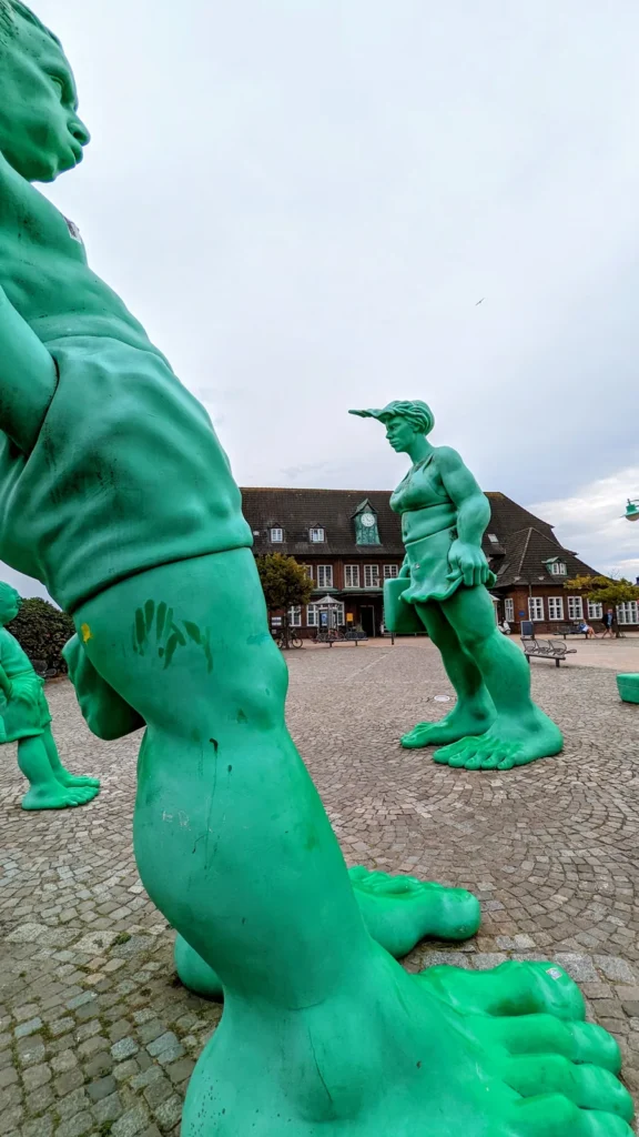 Grüne Figuren Reisende Riesen im Wind vor dem Bahnhof Westerland auf Sylt