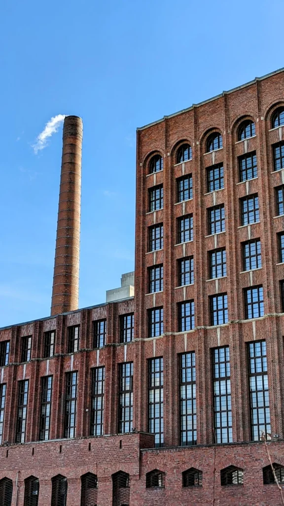 Hohe Backsteinfassade mit Bogenfenstern und Schornstein am Ullstein-Druckhaus in Tempelhof