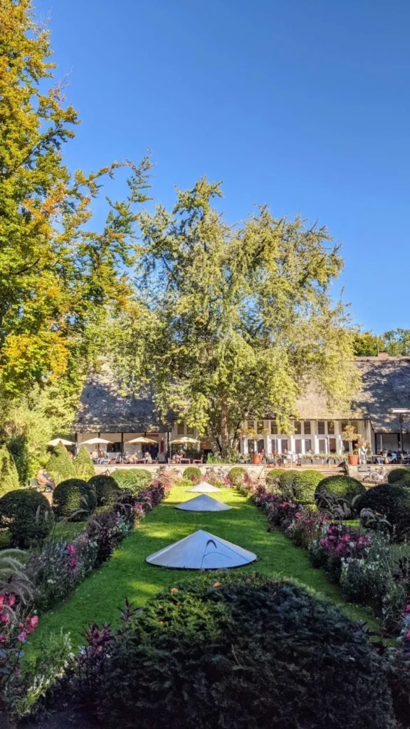 Beete und Rasen im Englischen Garten im Tiergarten, im Hintergrund das Teehaus mit Reetdach