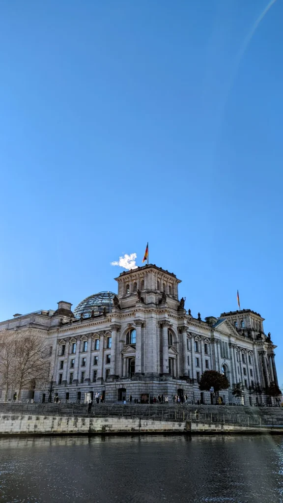 Reichstagsgebäude mit Glaskuppel und Fahne, von der anderen Seite der Spree gesehen