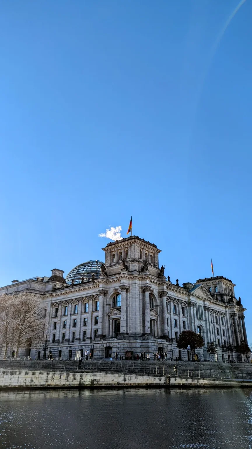 Reichstagsgebäude mit Glaskuppel und Fahne, von der anderen Seite der Spree gesehen