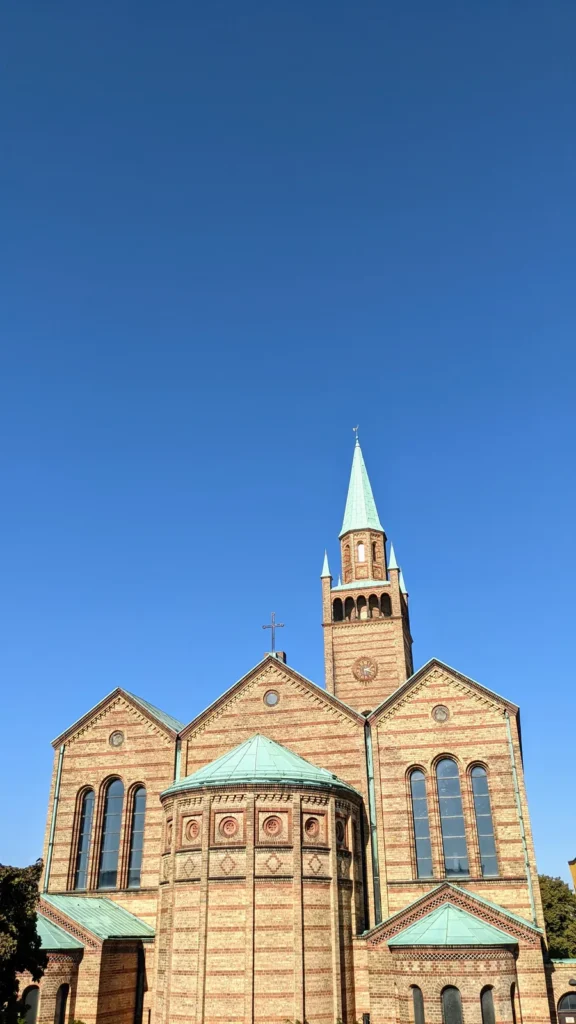 Backsteinfassade der St.-Matthäus-Kirche von Stüler mit Turm und grünem Spitzhelm