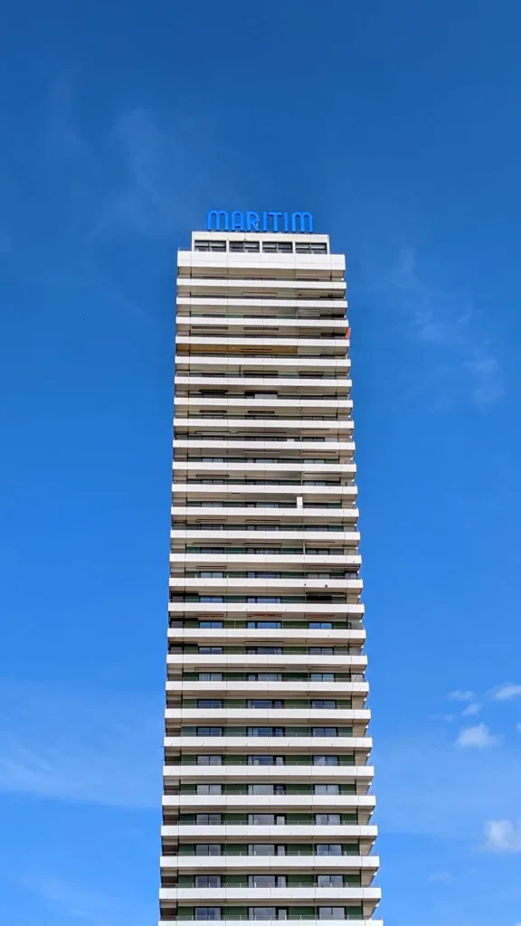 Das Maritim-Hochhaus in Travemünde mit blauem Schriftzug vor blauem Himmel