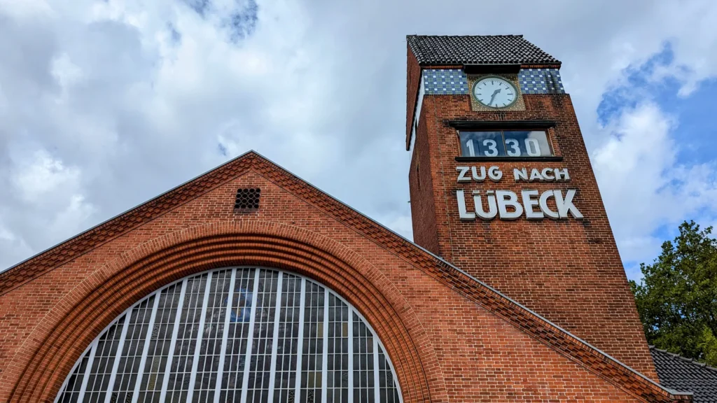 Backsteinbahnhof mit Uhrenturm und der Anzeige Zug nach Lübeck am Strandbahnhof von Travemünde