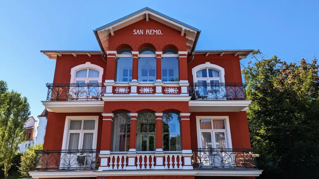 Rot gestrichenes Haus San Remo in der Maxim-Gorki-Straße in Heringsdorf mit weißen Balkonen