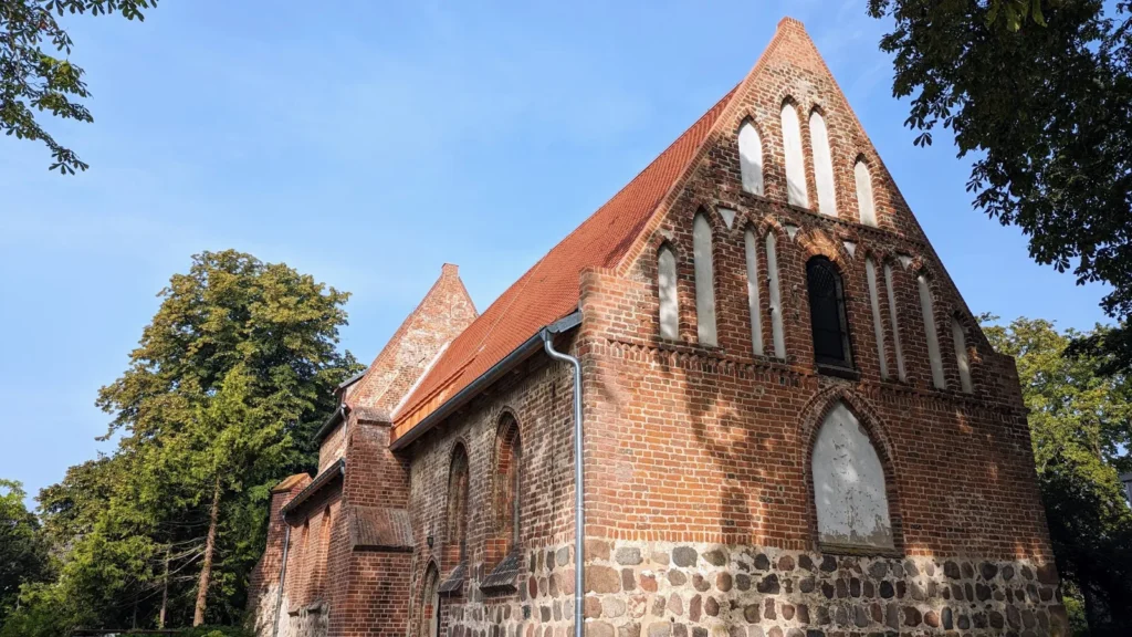 Giebel der Backsteinkirche von Koserow mit Spitzbogenfenstern über dem Feldsteinsockel