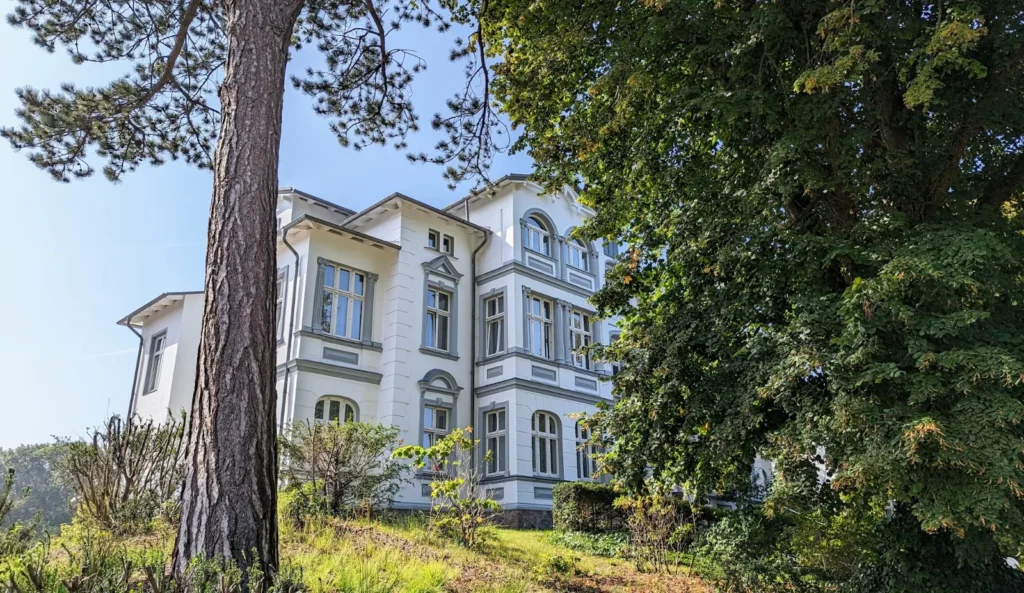Weiße Villa zwischen Kiefern und Laubbäumen an der Strandpromenade von Zinnowitz
