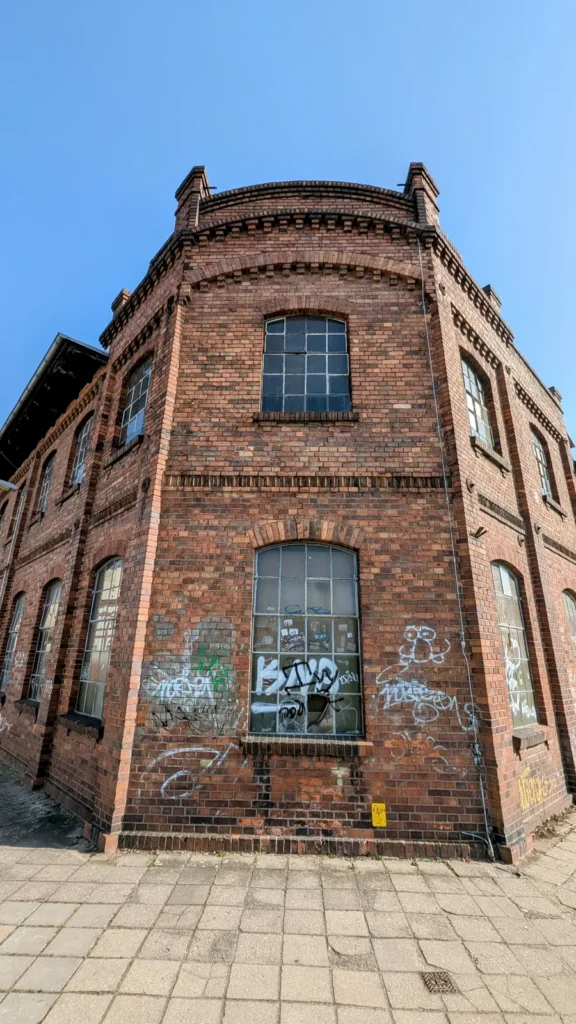 Backsteingebäude mit großen Sprossenfenstern und Graffiti im Erdgeschoss