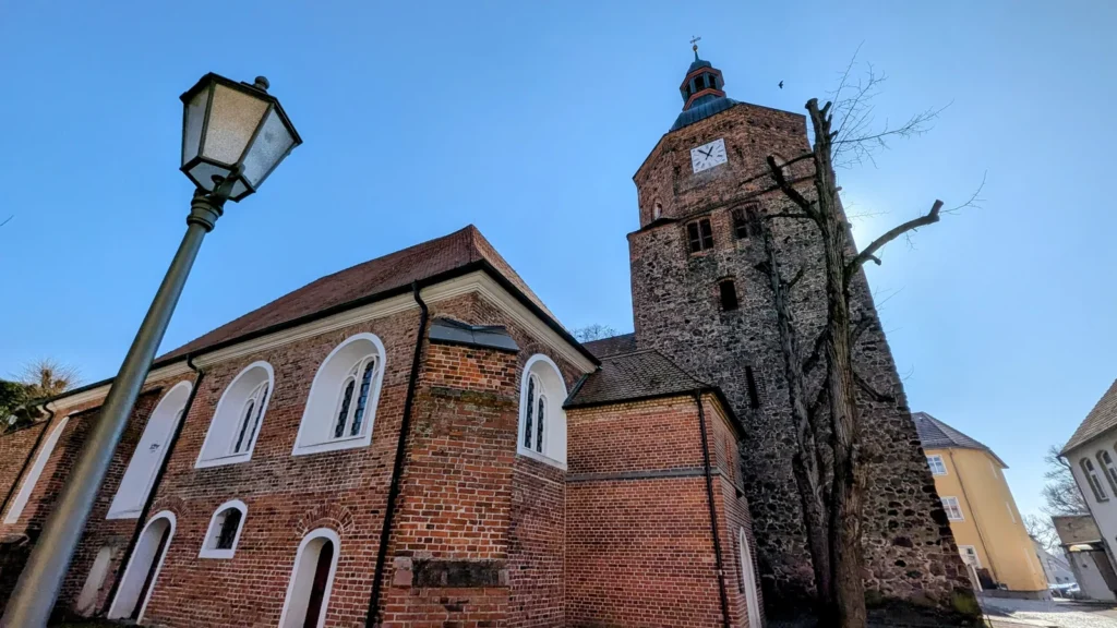 Backsteinkirche mit Feldsteinturm in Vetschau, davor eine Laterne