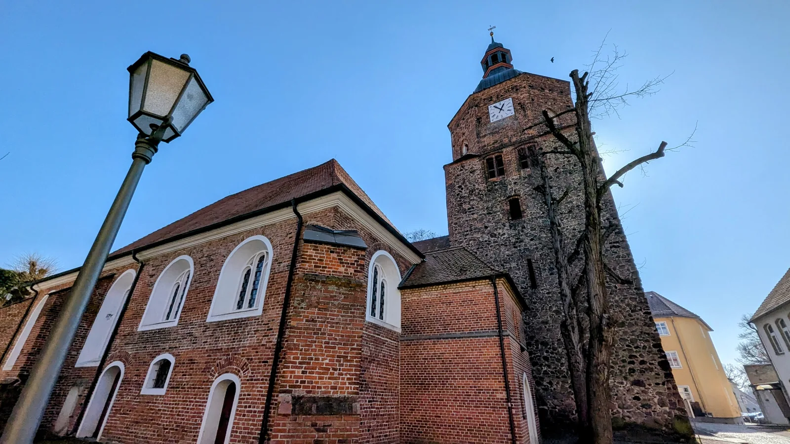 Backsteinkirche mit Feldsteinturm in Vetschau, davor eine Laterne