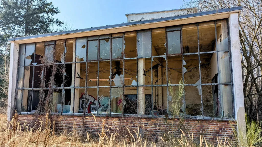 Fensterfront einer Backsteinhalle mit zerbrochenen Scheiben