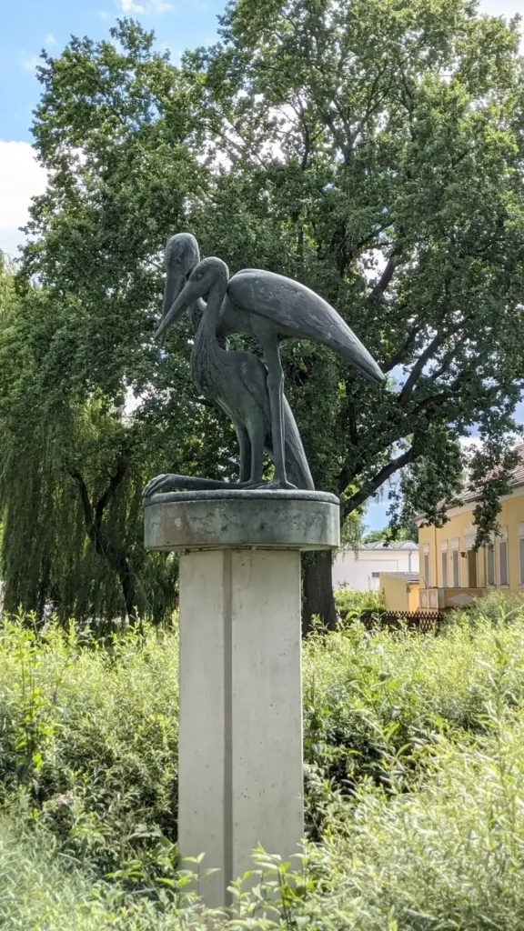 Bronzeskulptur auf einem Sockel vor Bäumen nahe dem Dorfteich im alten Dorfkern von Wartenberg