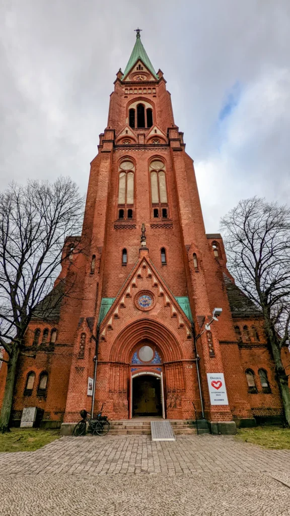 Neugotischer Backsteinturm der Neuen Nazarethkirche am Leopoldplatz mit grüner Kupferspitze vor bewölktem Himmel