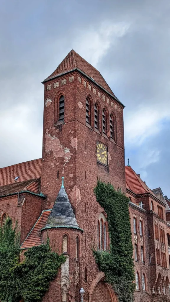 Backsteinturm der Osterkirche im Sprengelkiez mit rundem Treppenturm und Efeu an der Fassade