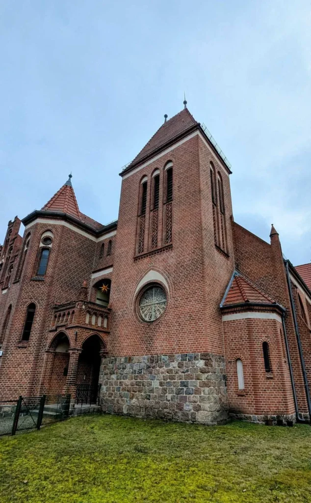 Rote Backsteinkirche mit Turm, Rundfenster und Feldsteinsockel, die Lutherkirche an der Hielscherstraße in Wilhelmsruh