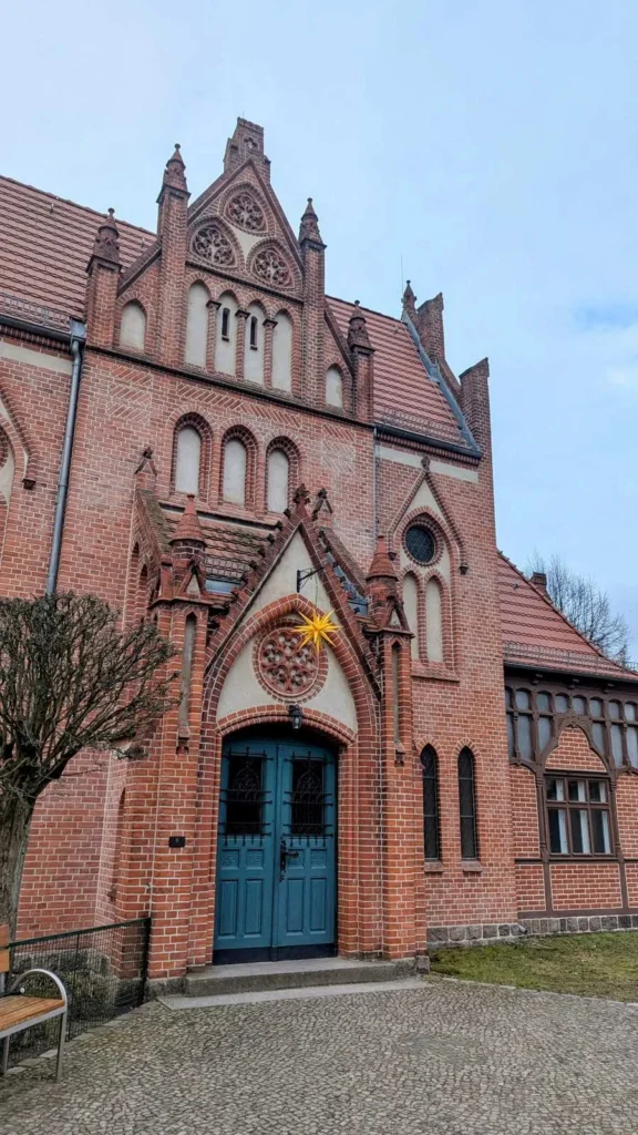 Giebel und Eingang der Lutherkirche in Wilhelmsruh mit blauer Tür und Backsteinornamenten