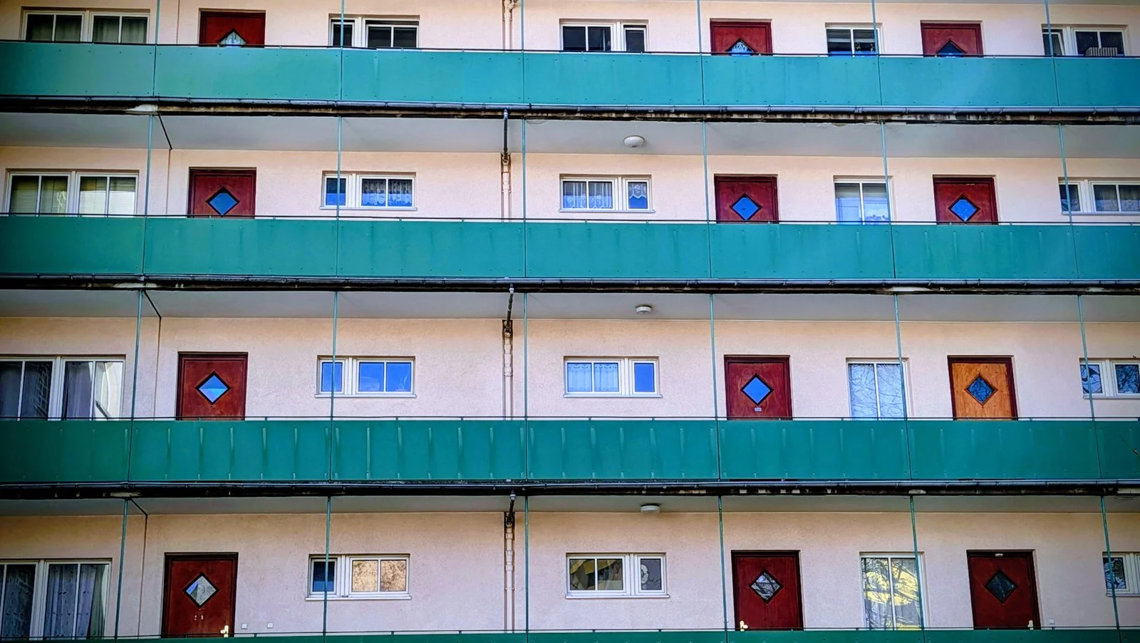 Wohnhaus in Wilmersdorf mit türkisgrünen Balkonbrüstungen und roten Fenstern in der Fassade