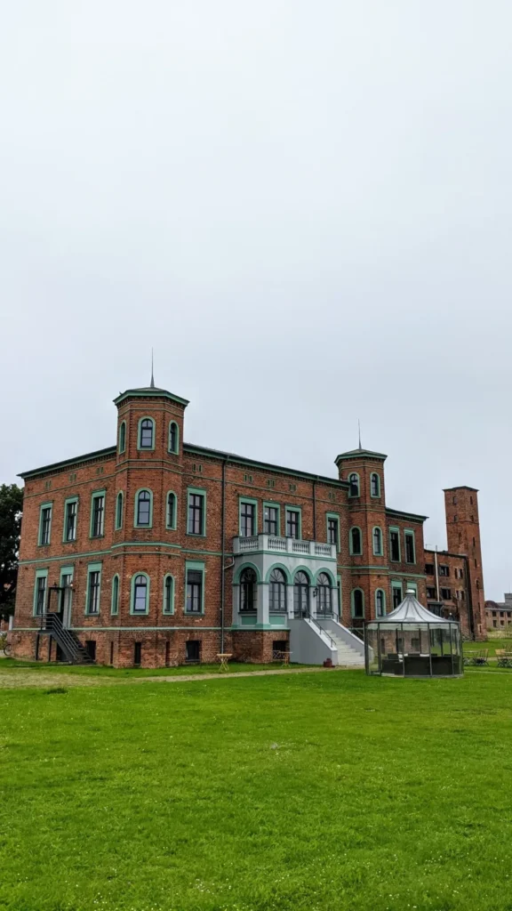 Backsteinvilla mit Turm und Wintergarten, davor eine Wiese, bei Wittenberge