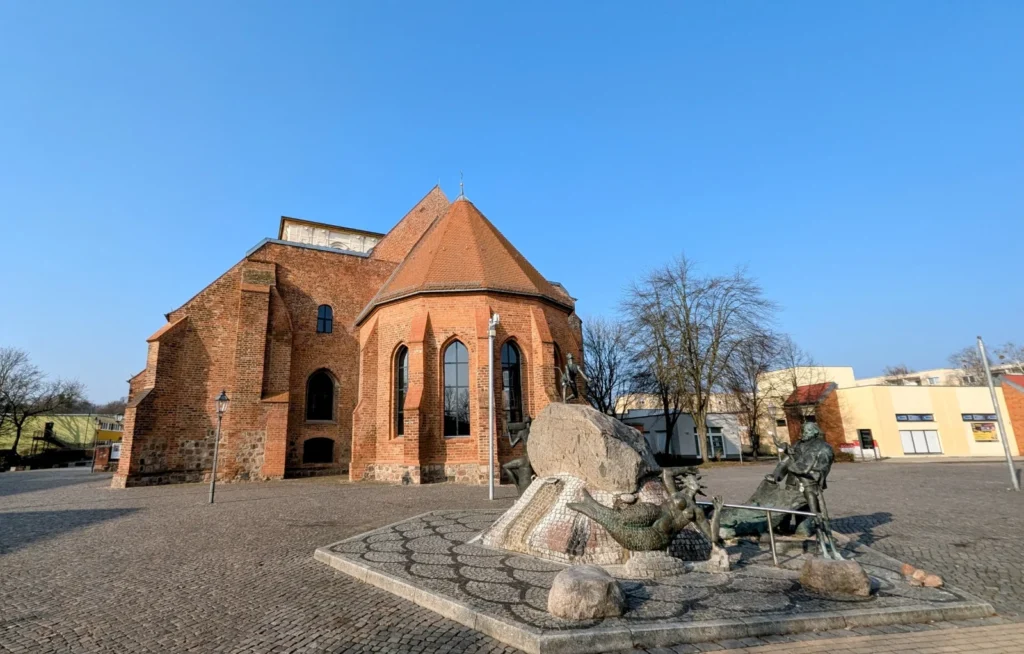 Backsteinchor der Marienkirche am Markt in Wriezen, davor der Lebensbrunnen mit Findlingen und Bronzefiguren