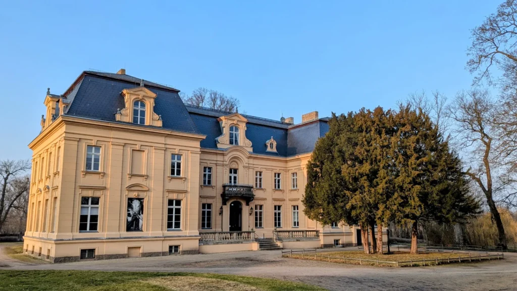 Schloss Altranft, ein gelber Bau mit dunklem Mansarddach und Balkon über dem Eingang